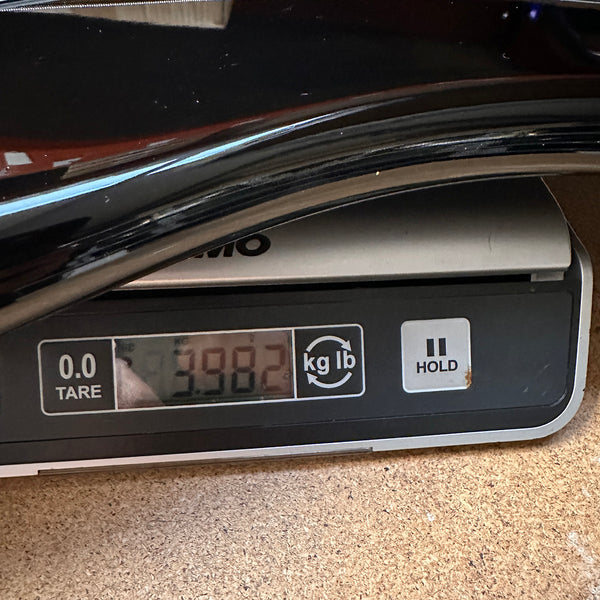 Digital scale showing weight of guitar as 3.982 pounds on wooden surface with part of guitar body visible.