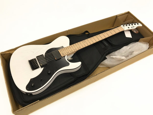 FGN electric guitar with white body, black pickguard, and maple neck inside open cardboard box with black gig bag