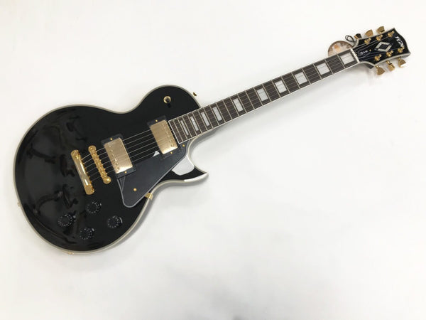 Black electric guitar with gold hardware and dual humbucker pickups, featuring a rosewood fretboard and trapezoid inlays on a white background.