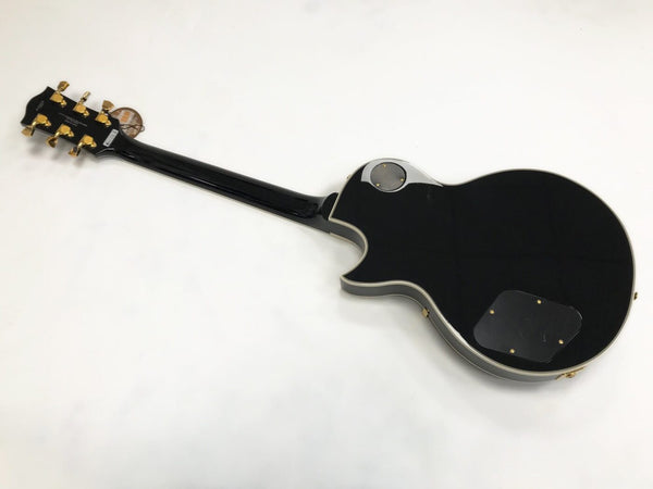 Back view of black electric guitar with gold tuning pegs and white binding on body and neck from Coffee House Guitars product listing