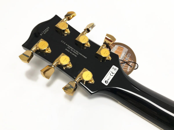Black guitar headstock with gold tuning pegs, serial number K170532, made in Japan, featuring C.F.S. system and compliance stickers, photographed on white background for Coffee House Guitars.