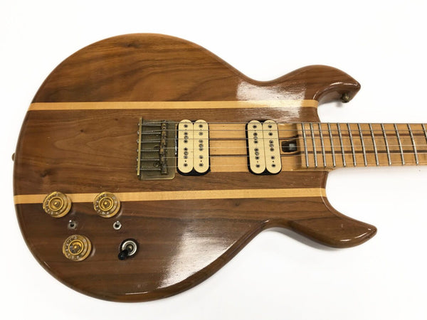 Vintage natural wood finish electric guitar with dual cream humbucker pickups, brass bridge, three control knobs, and maple neck with fretboard.