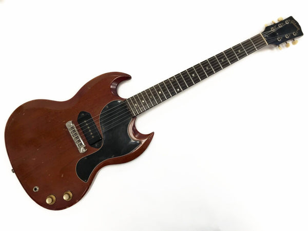Vintage Gibson SG electric guitar with single P-90 pickup and rosewood fretboard, worn brown finish and black pickguard on white background.