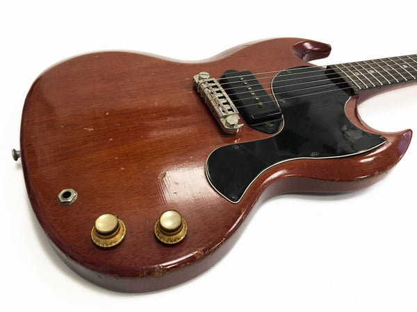 Vintage worn electric guitar with mahogany body, black pickguard, two control knobs, and single pickup on white background
