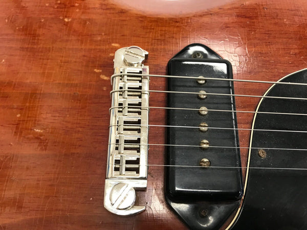 Close-up of vintage electric guitar bridge, strings, and black single-coil pickup on a worn sunburst wooden body
