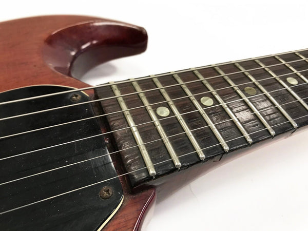 Close-up of vintage electric guitar neck, fretboard, strings, and pickup with worn wood finish and dot inlays on a white background