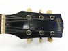 Close-up of vintage Gibson guitar headstock with six tuning pegs and worn black finish on white background