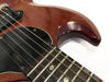 Close-up of vintage electric guitar body and neck with visible wear and aging on brown finish, black pickguard, and metal strings on rosewood fretboard