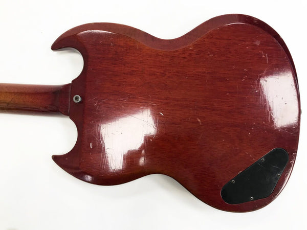 Vintage cherry red electric guitar back with worn finish and black plastic control cavity cover on white background
