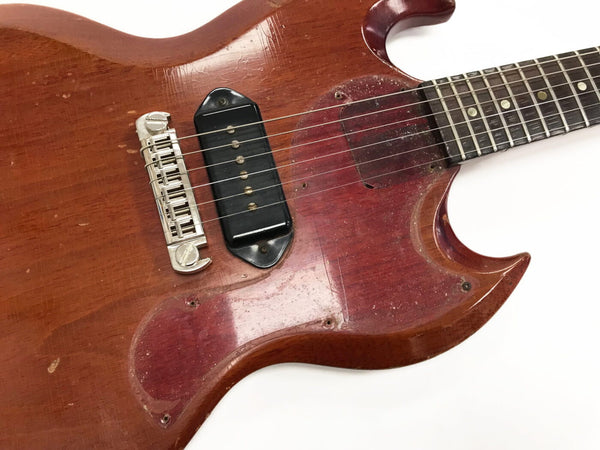 Close-up of vintage worn cherry red electric guitar body with single black pickup and silver bridge by Coffee House Guitars