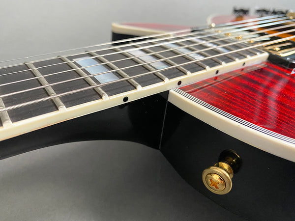 Close-up of electric guitar neck, fretboard, and body with red finish and gold strap button from Coffee House Guitars product listing