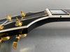 Close-up of black electric guitar headstock with gold tuning pegs and white binding on fretboard, Coffee House Guitars product image