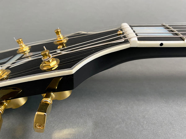 Close-up of black electric guitar headstock with gold tuning pegs and white binding on fretboard, Coffee House Guitars product image