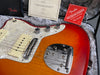 Close-up of Fender electric guitar with sunburst finish, pearl white pickguard, dual knobs, and Fender bridge, displayed with certificate and Fender free online lessons card in guitar case lining