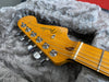 Close-up of Fender Jazzmaster electric guitar headstock with chrome tuning pegs resting on grey furry guitar case lining