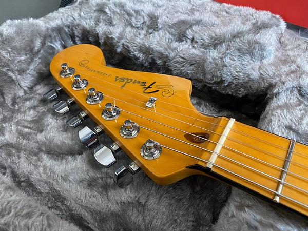 Close-up of Fender Jazzmaster electric guitar headstock with chrome tuning pegs resting on grey furry guitar case lining