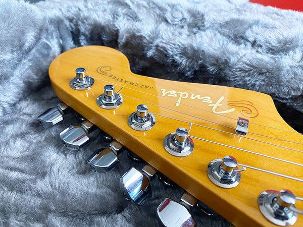 Close-up of Fender Jazzmaster guitar headstock with chrome tuners on gray plush case lining