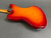 Back view of electric guitar with sunburst red and orange finish and maple neck on gray background