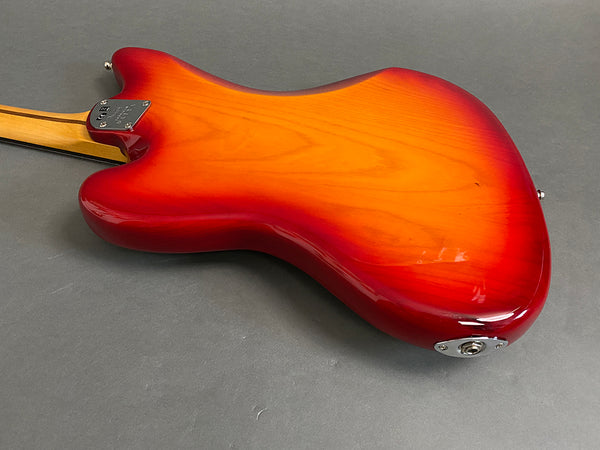 Back view of electric guitar with sunburst red and orange finish and maple neck on gray background