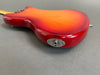 Back close-up view of red sunburst electric guitar body with silver output jack plate on gray surface