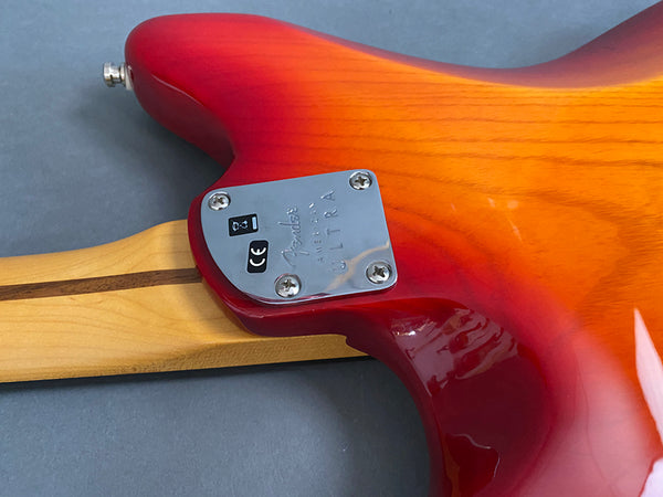 Close-up of Fender American Ultra electric guitar neck plate and back body in sunburst finish showing joint and wood grain details
