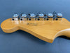 Close-up of maple guitar headstock with six chrome tuning pegs, serial number US19081447, made in Corona, California on blue background