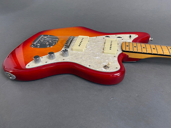 Electric guitar with sunburst finish, white pearloid pickguard, maple fretboard, and chrome control knobs on gray background