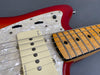 Close-up of red electric guitar with maple fretboard and white pearloid pickguard showing Fender pickup and control switches