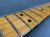 Close-up of guitar maple fretboard with metal frets and steel strings on dark background
