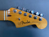 Close-up of Fender Jazzmaster guitar headstock with tuning pegs and strings on gray background