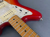 Close-up of red Fender electric guitar body, maple neck, pearl pickguard, and vintage-style pickups with metal frets and black dot inlays on fretboard
