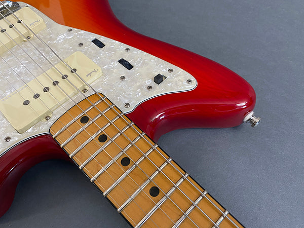 Close-up of red Fender electric guitar body, maple neck, pearl pickguard, and vintage-style pickups with metal frets and black dot inlays on fretboard