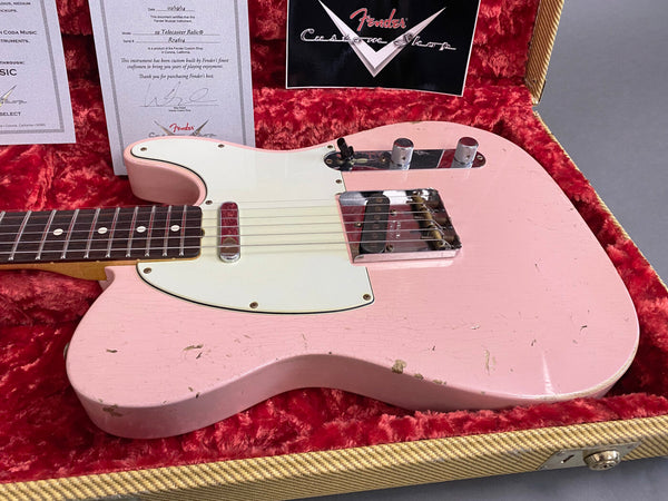 Fender Custom Shop 1959 Telecaster Relic electric guitar in pink finish with white pickguard resting inside red velvet-lined vintage guitar case with Fender certificate of authenticity visible behind the guitar.