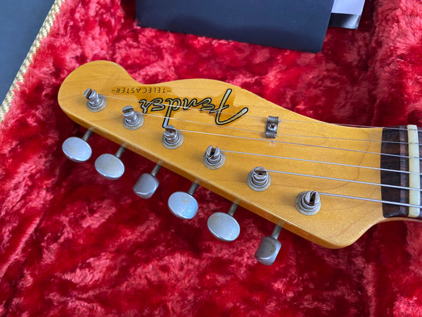 Close-up of Fender Telecaster guitar headstock with tuning pegs on red plush guitar case lining