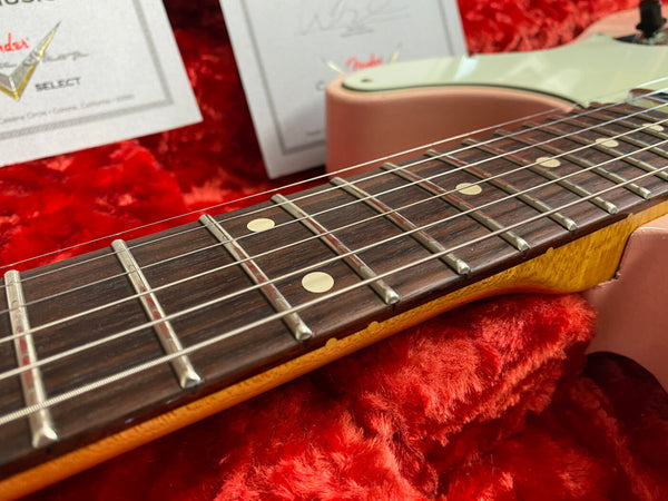 Close-up of rosewood fretboard and steel strings on a Fender electric guitar with a cream body in a red plush case