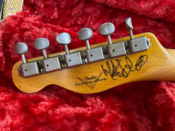 Fender Custom Shop guitar headstock with vintage tuning pegs on red plush case interior, signed by artist