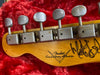Close-up of vintage Fender Custom Shop guitar headstock tuners with signature, set against a red plush guitar case interior