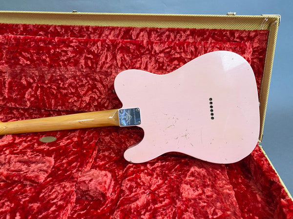 Back of pink Gibson guitar body with maple neck and chrome neck plate inside vintage red plush-lined tweed guitar case