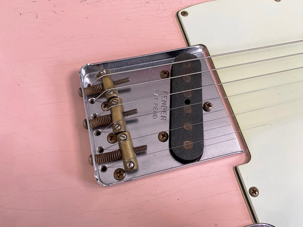 Close-up of vintage Fender Telecaster guitar bridge and single-coil pickup on pink body with white pickguard and metal components
