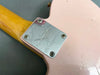 Close-up of the neck plate on a pink Fender Custom Shop electric guitar featuring the Godamusic logo and serial number R74614 with a natural wood neck.