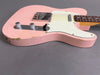 Close-up of pink electric guitar body with white pickguard and two chrome control knobs showing vintage wear and paint chips on gray background
