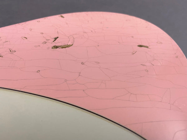 Close-up of pink guitar body with visible wear, cracks, and paint chips, highlighting vintage character and aging details.