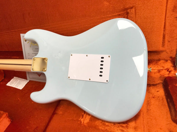 Back view of light blue electric guitar with white backplate and gold neck plate inside orange plush guitar case