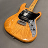 Natural wood finish electric guitar with black pickguard, dual humbucker pickups, chrome bridge, and metal control plate with knobs and switches on gray background