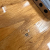 Close-up of light brown wood grain and finish on electric guitar body with metal plate and screws.
