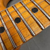 Close-up of maple guitar fretboard with metal frets, black dot inlays, and steel guitar strings on dark background