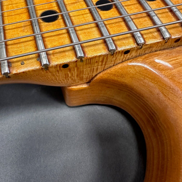 Close-up of guitar neck and body joint showing detailed wood grain and metal frets, highlighting craftsmanship of Coffee House Guitars electric guitar.