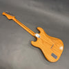 Back view of natural wood electric guitar with six tuning pegs and chrome neck plate on gray background