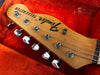 Close-up of Fender Telecaster guitar headstock with chrome tuning pegs inside red plush guitar case