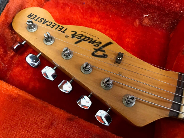 Close-up of Fender Telecaster guitar headstock with chrome tuning pegs inside red plush guitar case